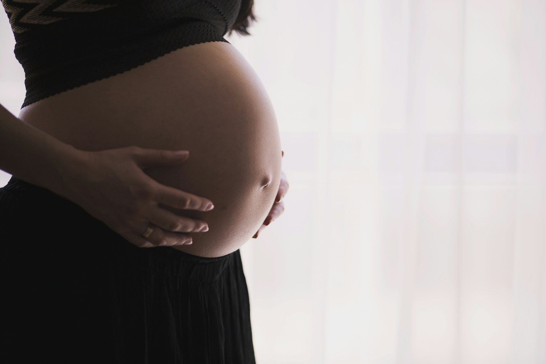 Schwangere Frau hält ihre Hände auf dem Bauch